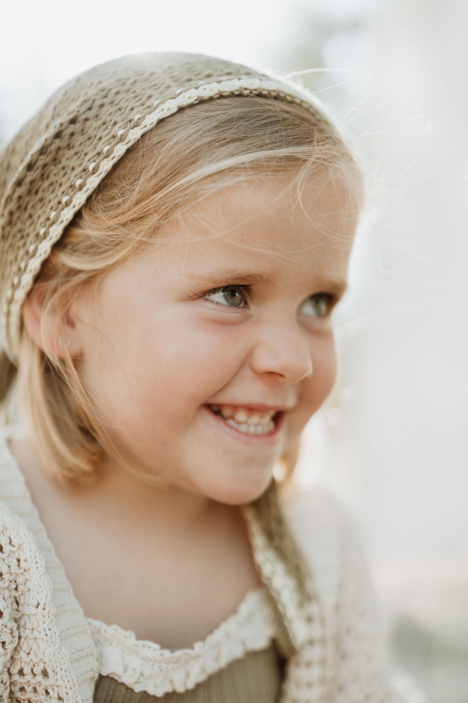 Candid portrait showing joyful expression and knit headband in soft lighting.