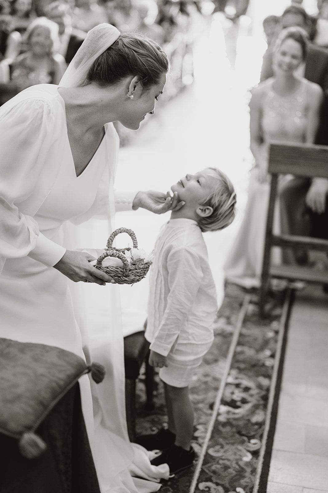 Sweet black and white moment captured during wedding ceremony with flower basket.