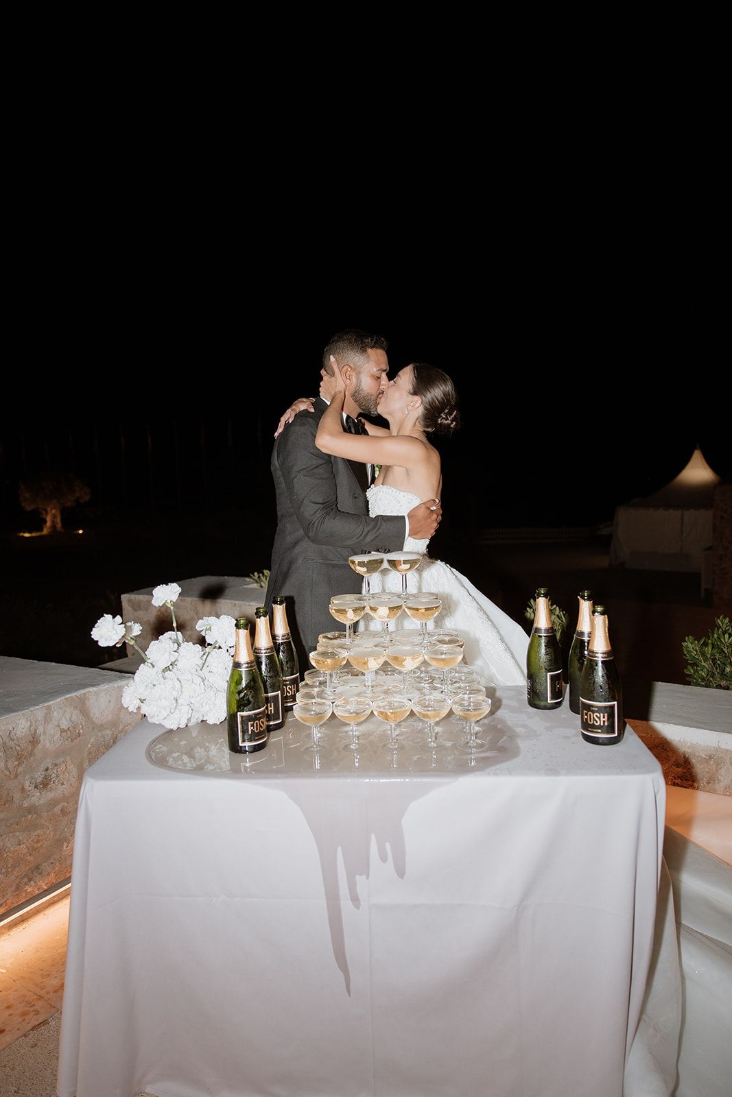 Newlyweds sharing a romantic moment behind their champagne tower display.