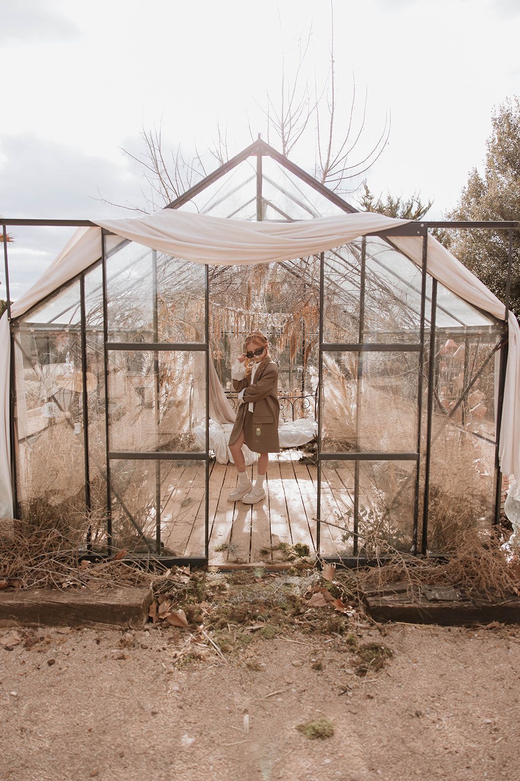 A greenhouse with glass walls and white fabric draping photographed in sepia tones.