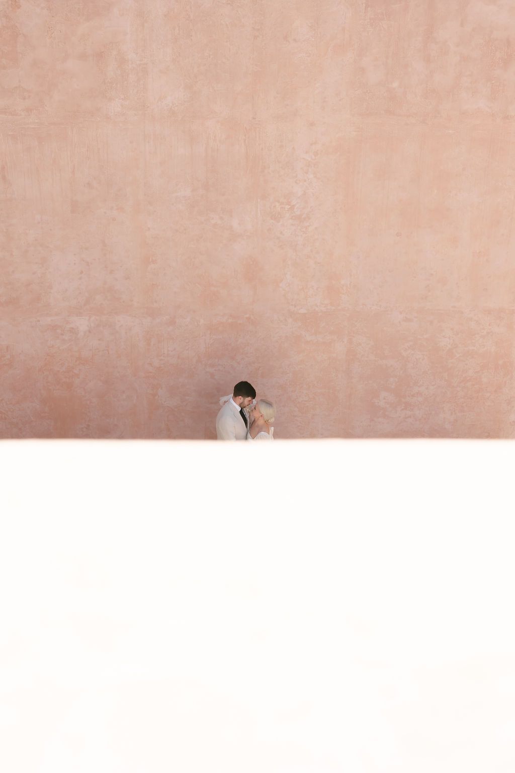 Modern minimalist architectural detail showing a pink stucco wall with a dramatic shadow line.