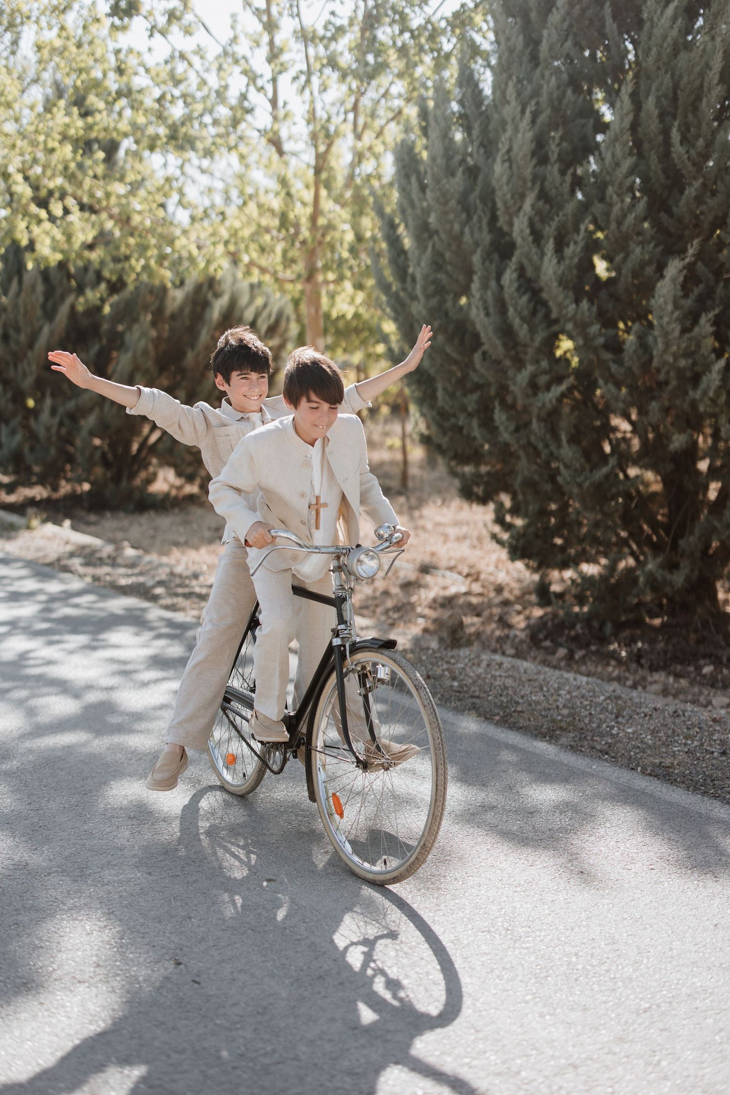 A romantic bike ride on a sunlit path with two people in matching beige outfits sharing a carefree moment together.