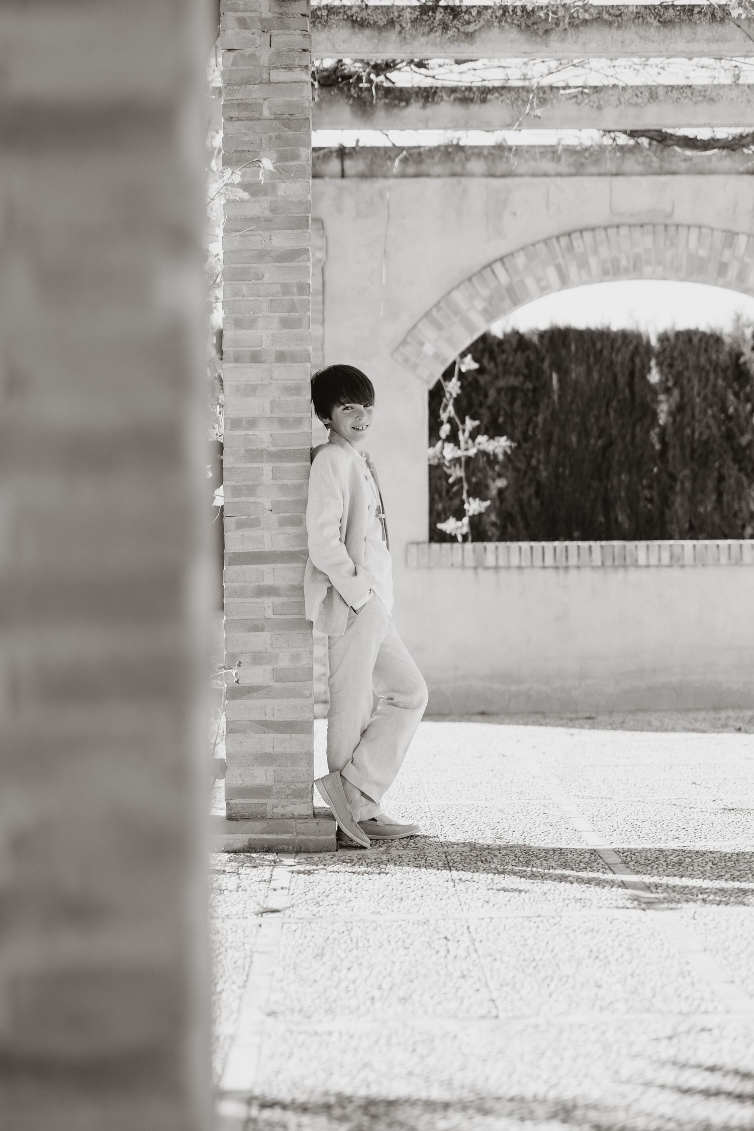 A black and white series of minimalist fashion photographs showing someone in a light colored suit against a brick wall.