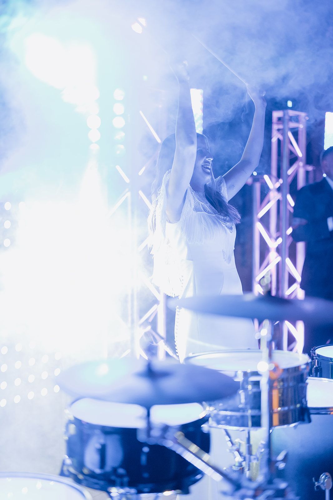 Silhouetted drummer performing on stage with dramatic backlighting and smoke effects.