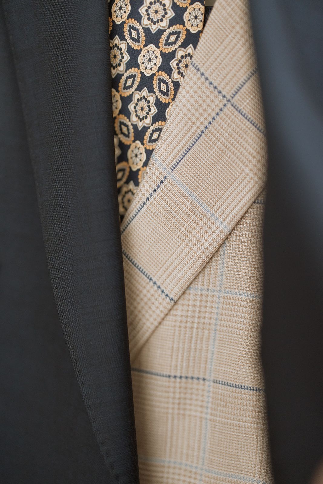 Close-up detail of suit jacket with patterned tie and plaid fabric.