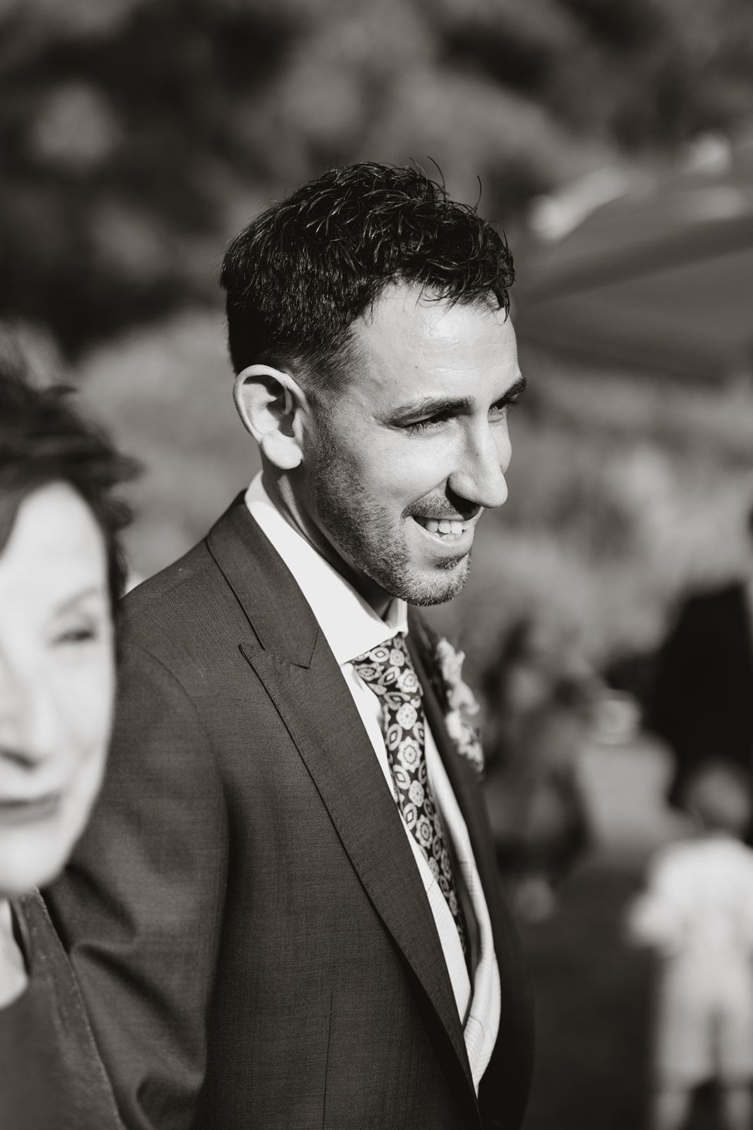A candid black and white portrait at an outdoor wedding celebration.