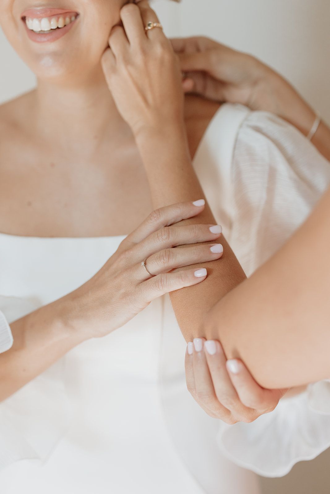 Close-up of hands wearing wedding rings and white fabric detail.