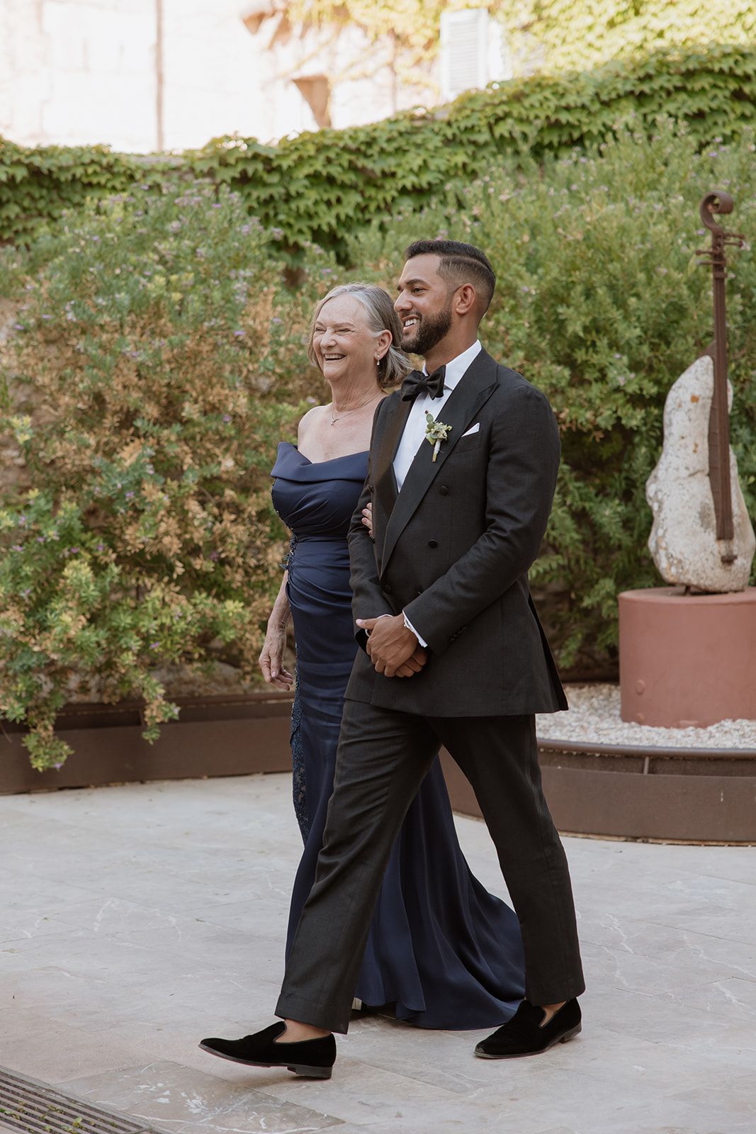 Formal couple walking and laughing together at an elegant outdoor venue.
