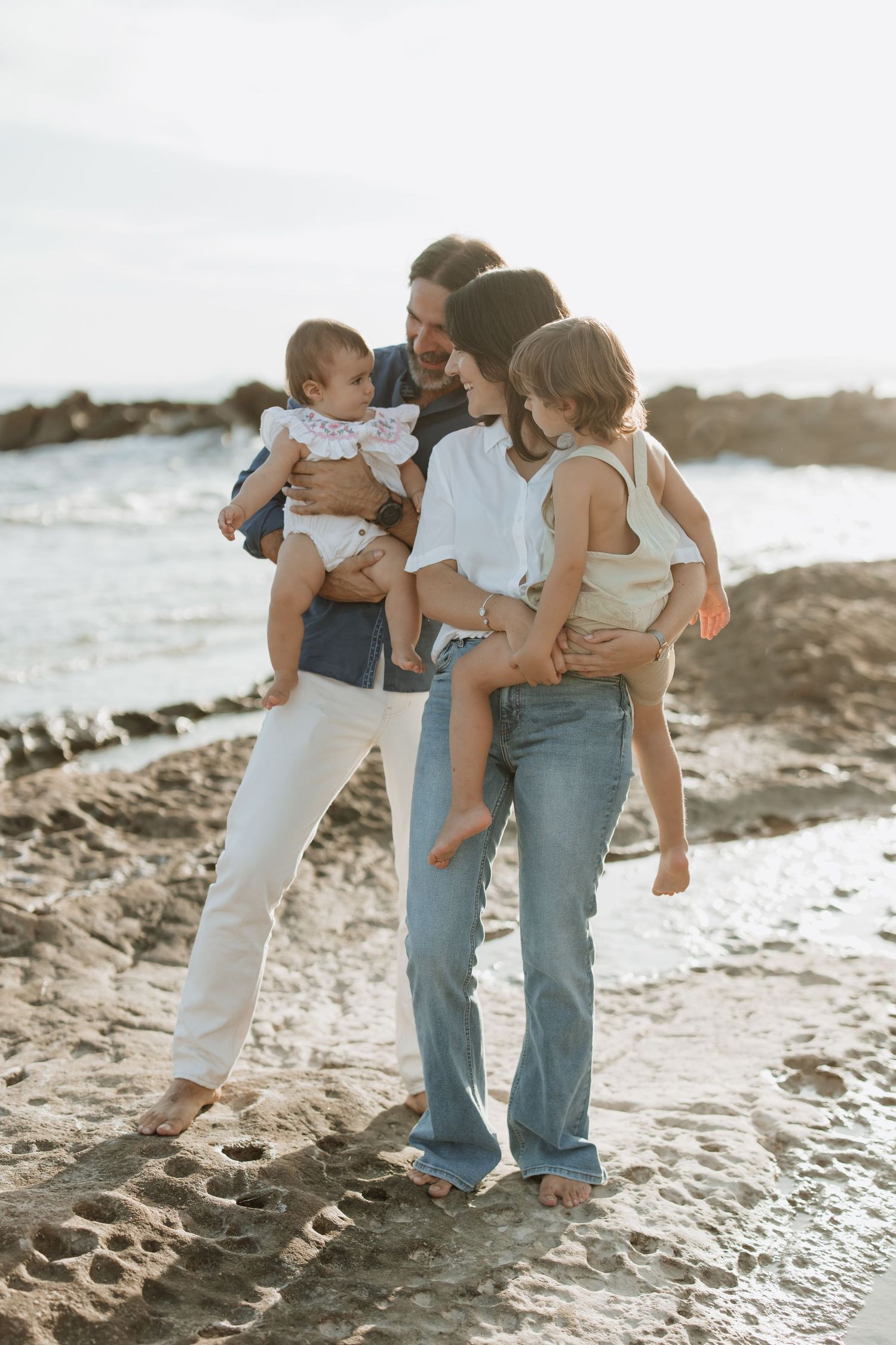 A family shares an intimate moment together on a beach at golden hour.