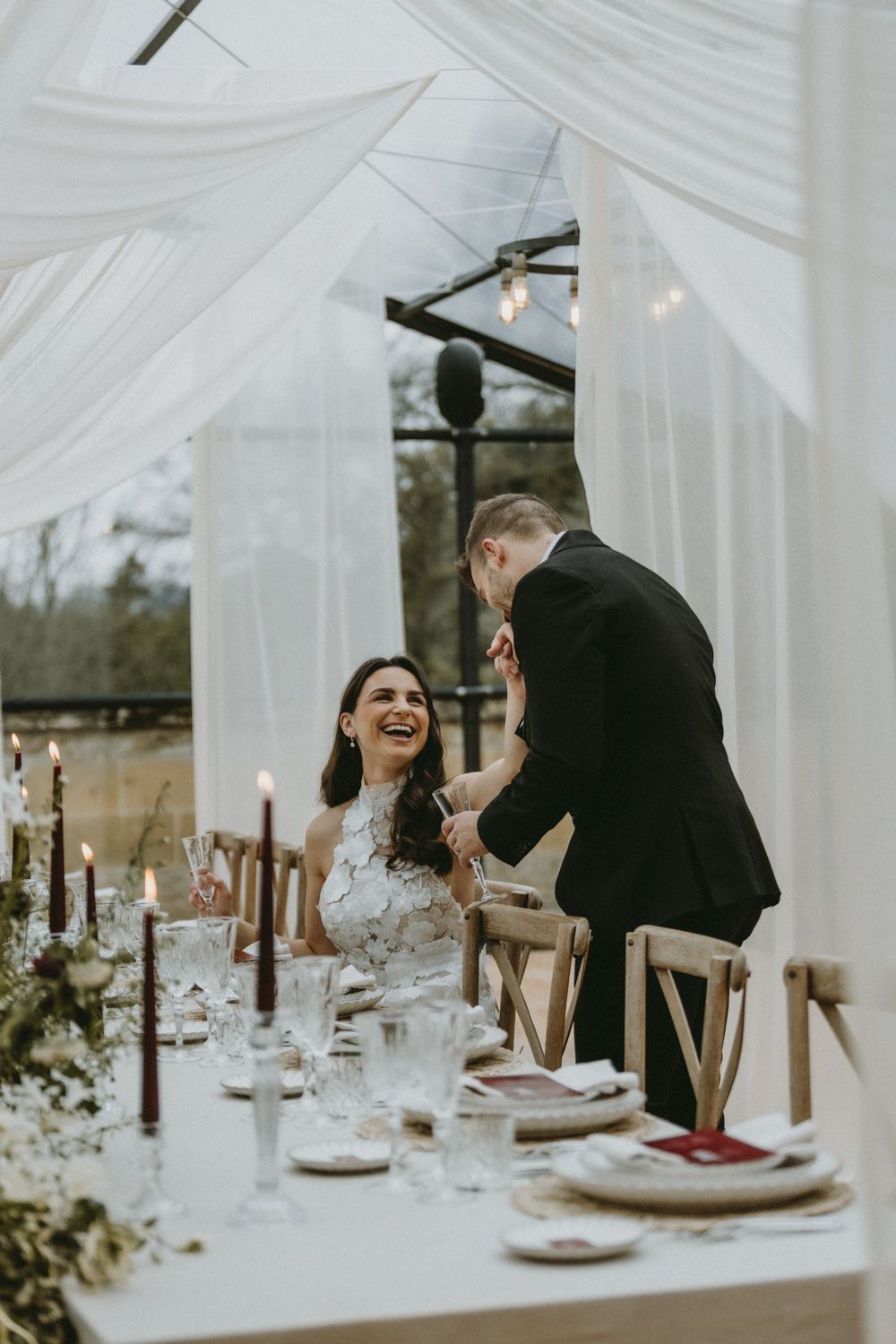 Elegant wedding reception table setup with white draping and intimate couple moment.