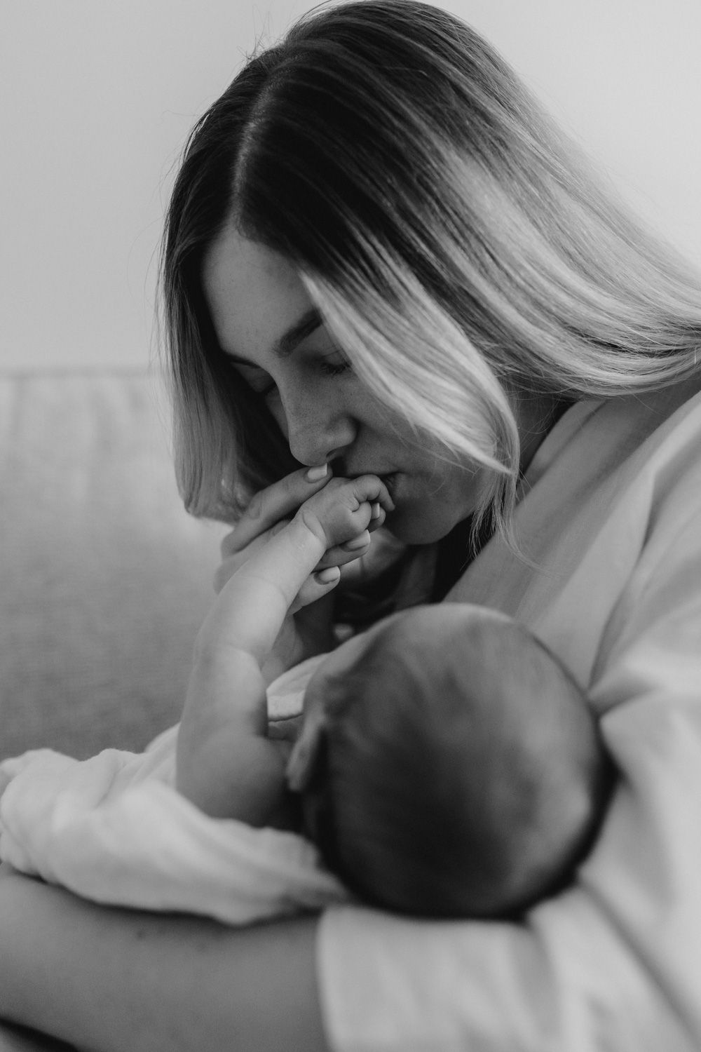 Black and white photograph capturing a tender moment with a newborn.