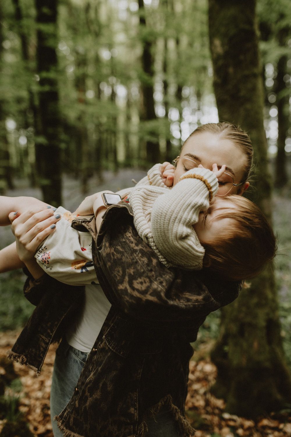Tender moment captured in a forest setting with warm natural lighting.
