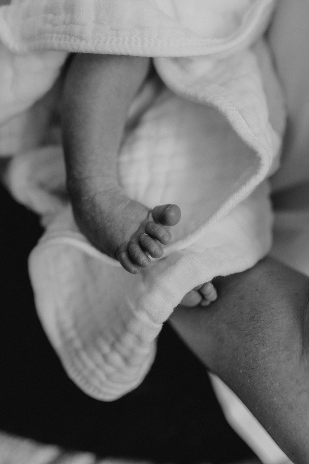 Black and white close-up of tiny baby feet wrapped in white fabric.