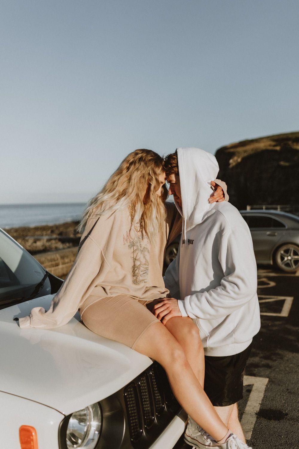A romantic moment on a coastal road with a couple embracing in soft lighting.