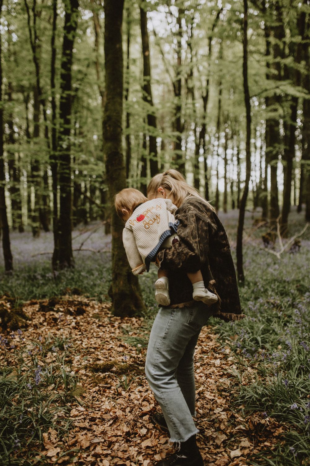 Dancing and spinning together among fallen autumn leaves in a wooded forest setting.