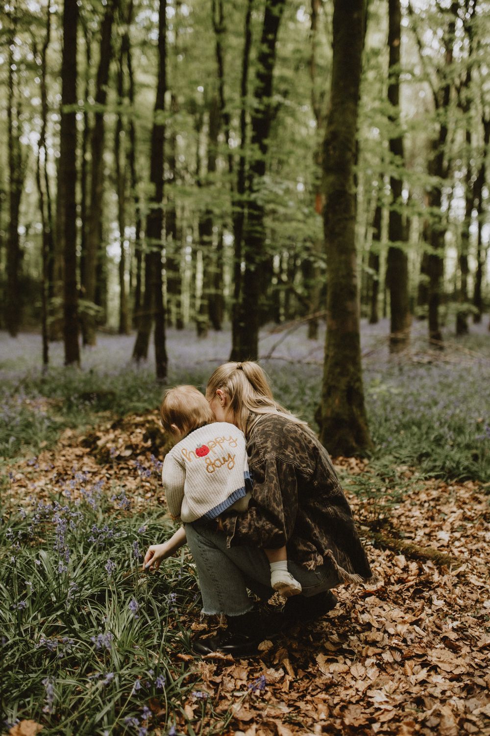 Exploring fallen leaves together in a serene forest environment.