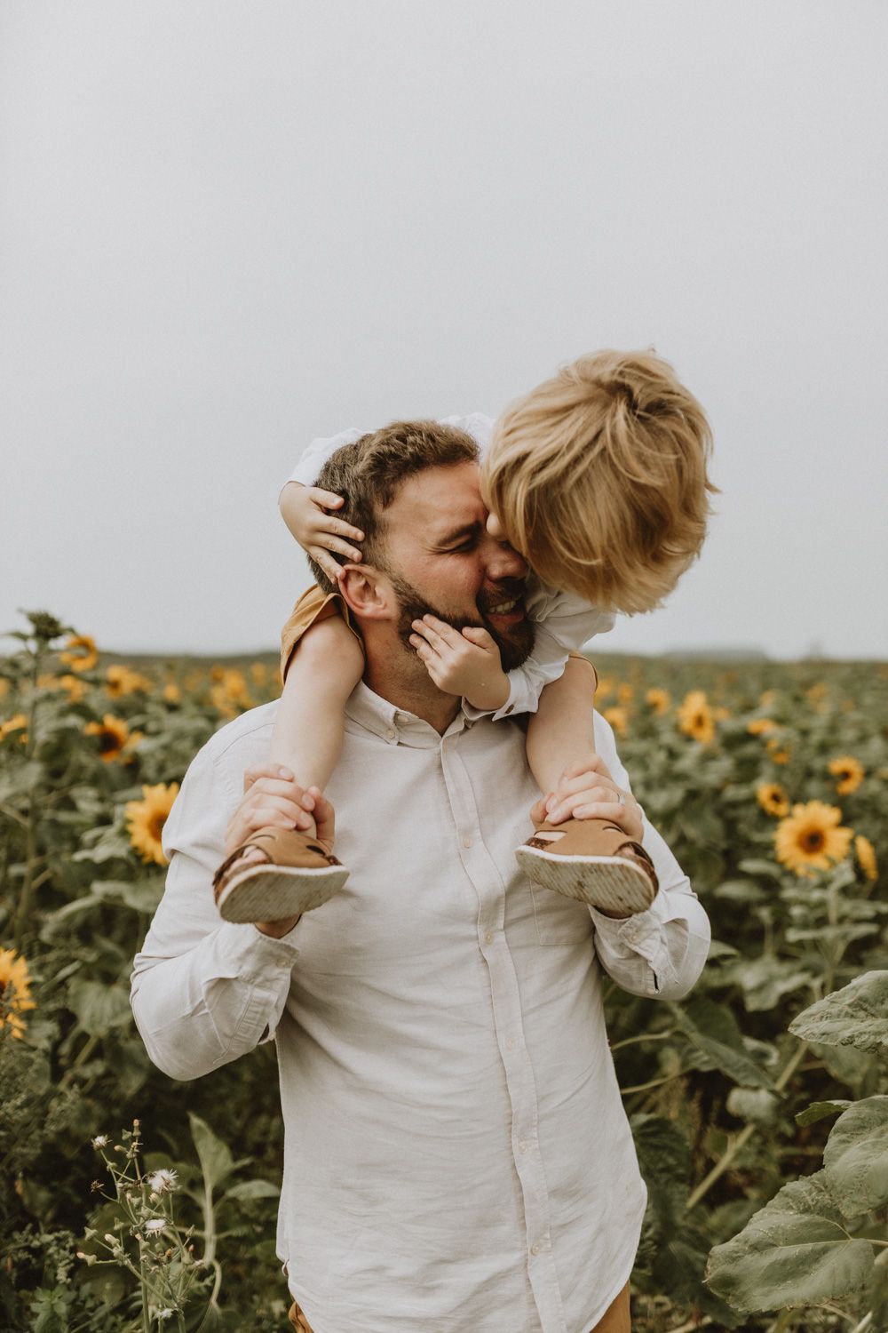 Intimate moment shared while giving piggyback ride in sunflower field.