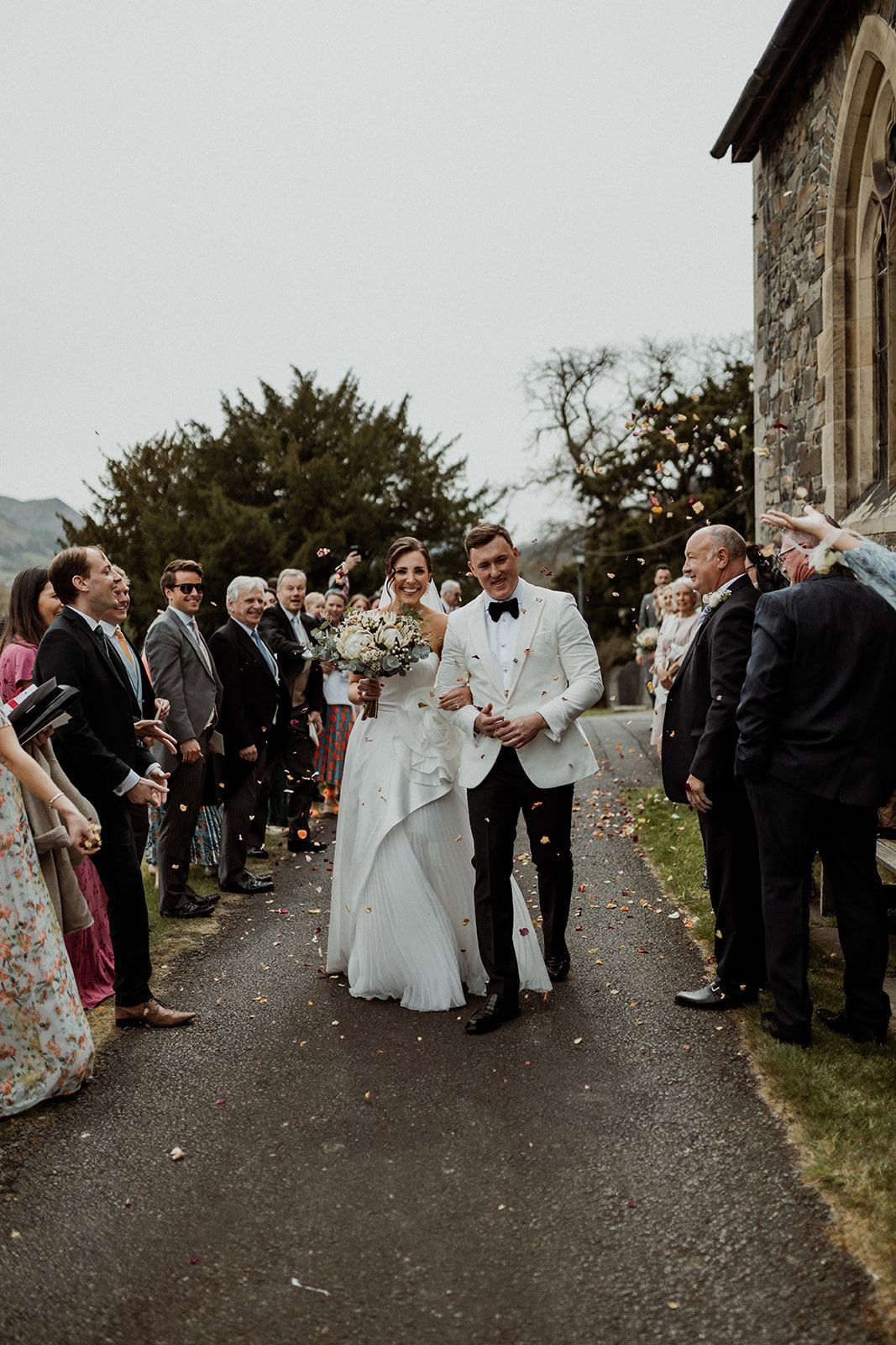 Wedding guests line a pathway to celebrate as the newlyweds walk through after their ceremony.