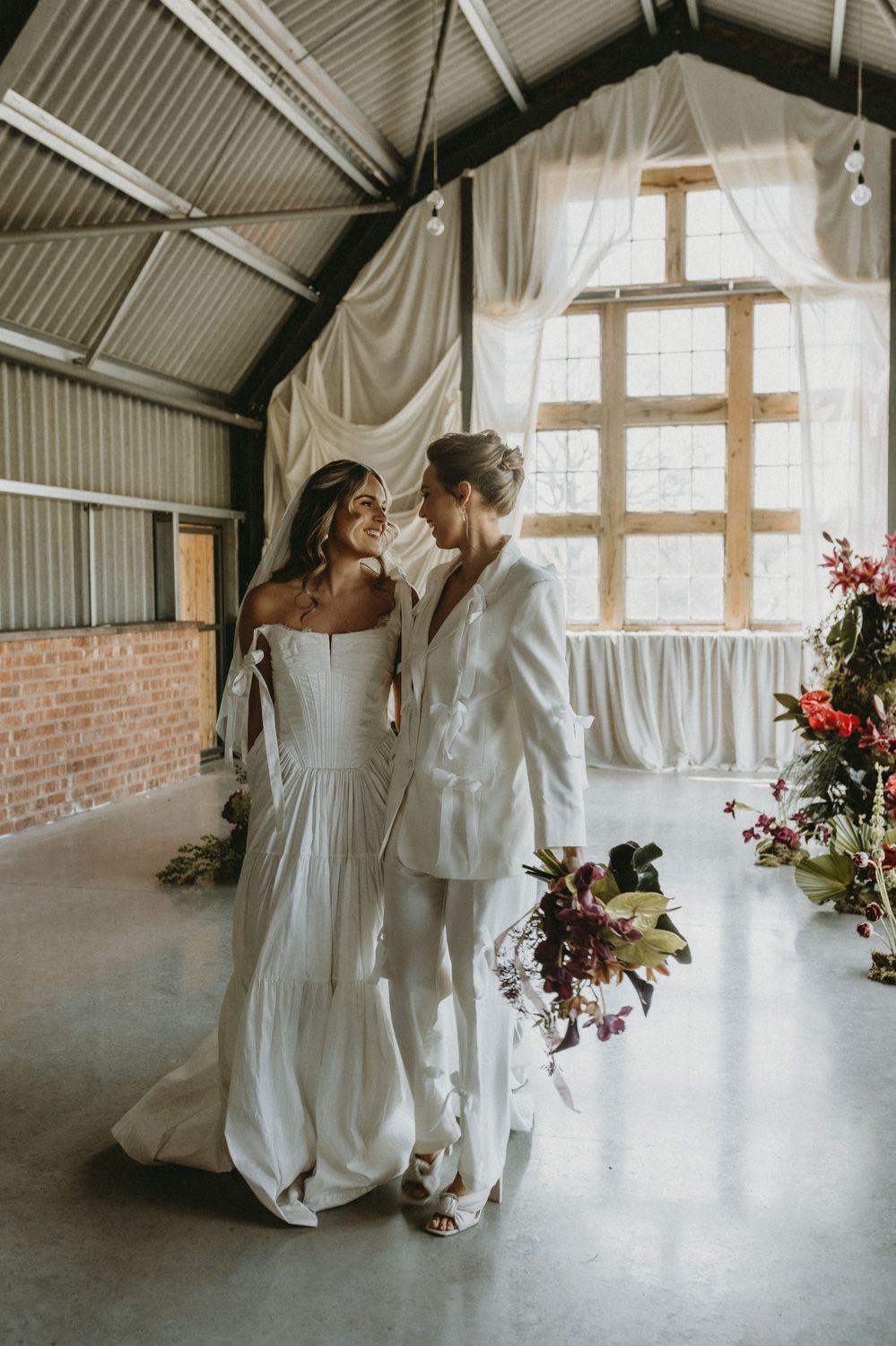 A romantic wedding moment in an industrial venue with flowing white curtains and natural light.