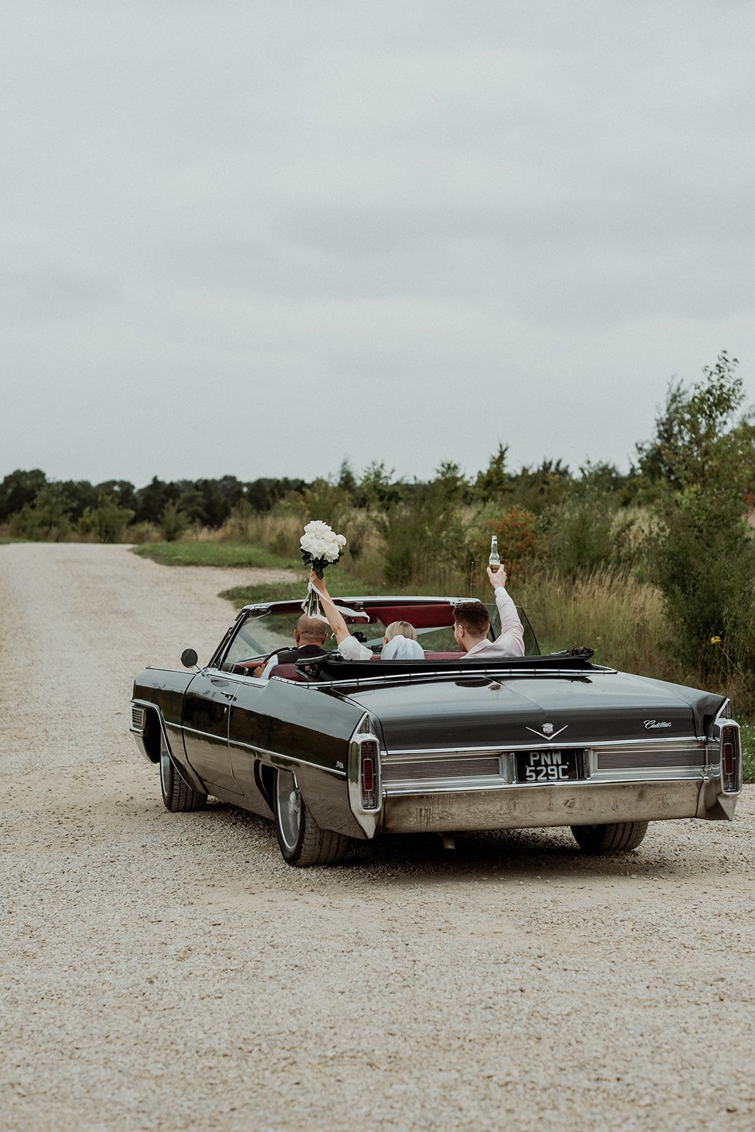 A sleek black vintage Cadillac convertible photographed at multiple angles on a gravel road.