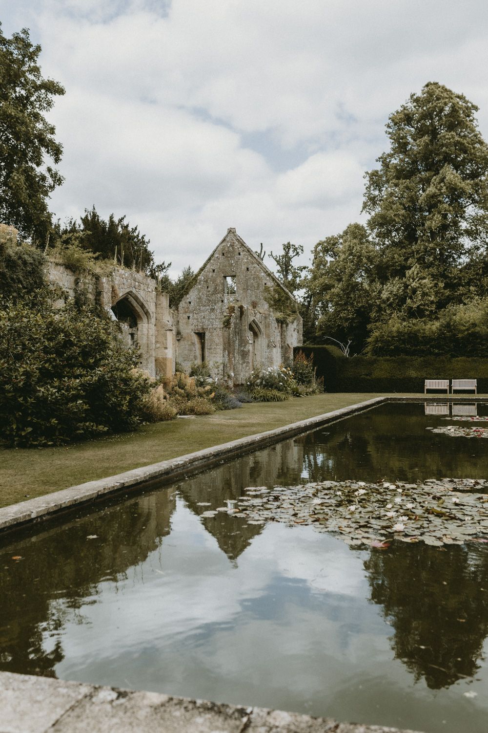 Ancient stone ruins reflected in a tranquil pond with lily pads.