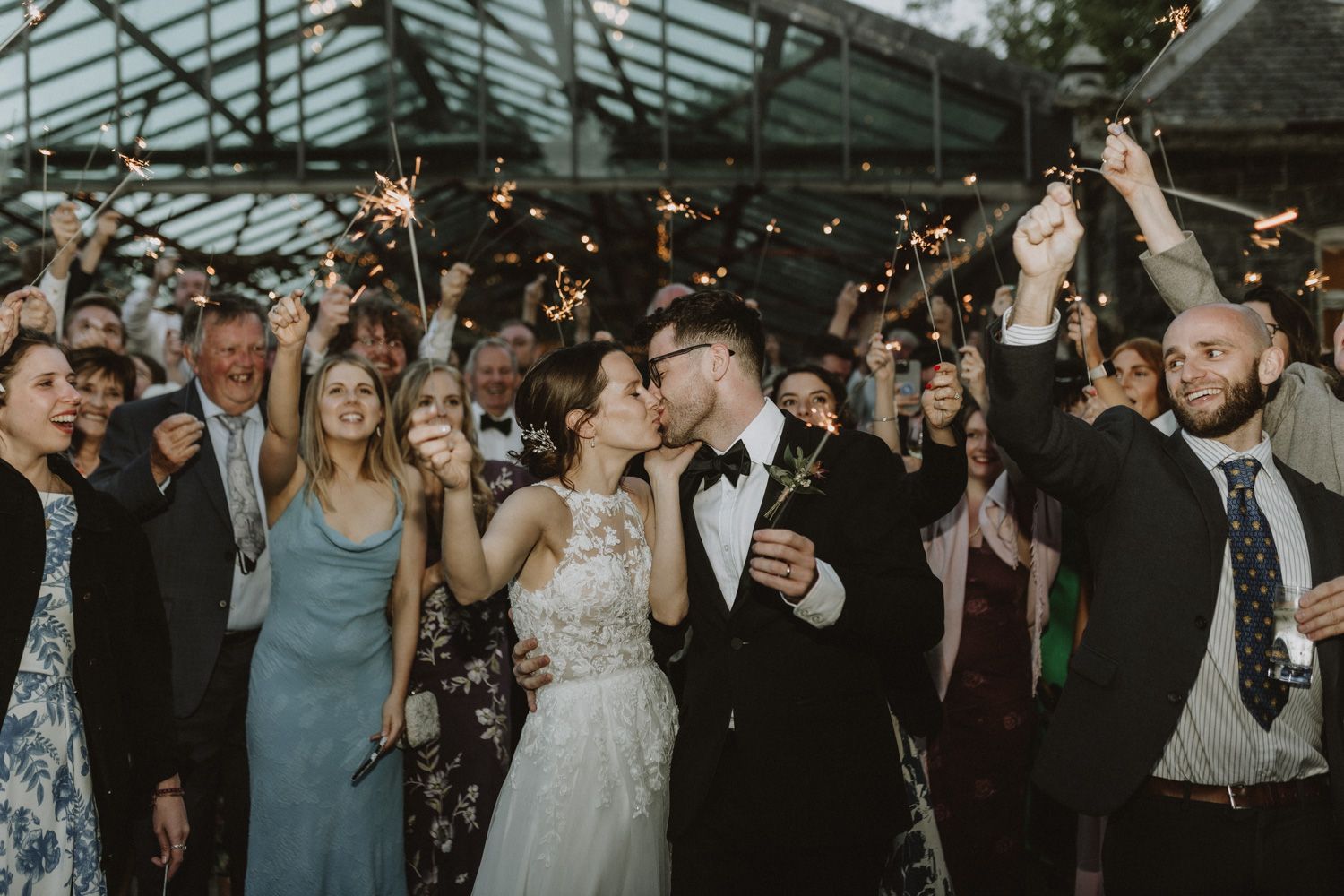 Wedding celebration with guests dancing and celebrating on the dance floor at an indoor reception.