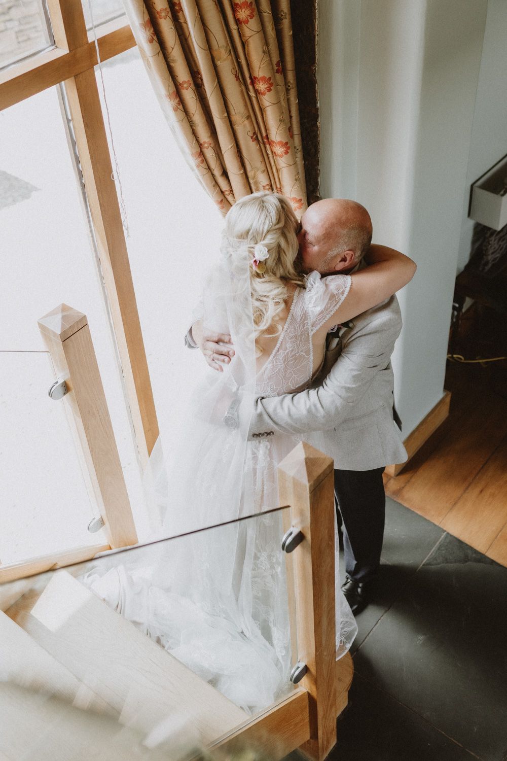 A heartfelt embrace captured during a wedding moment near a sunlit window.