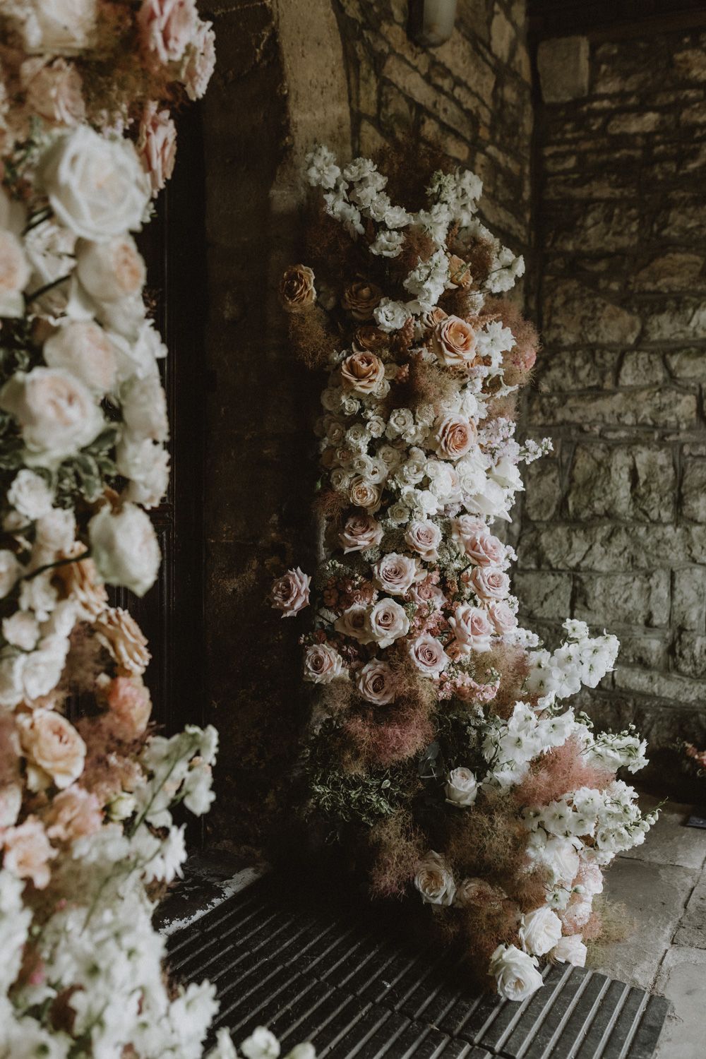 Delicate floral arrangements with white and pink roses adorn a stone wall interior.