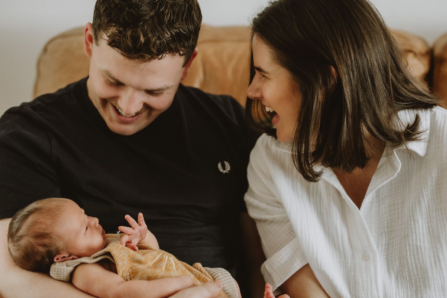 Family sharing a happy moment together on couch with newborn.