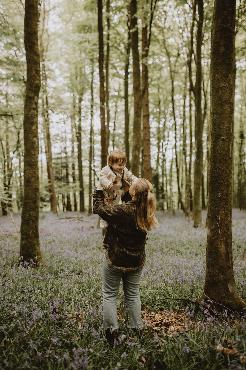 Person with a camera photographing in a beautiful forest filled with blooming wildflowers.