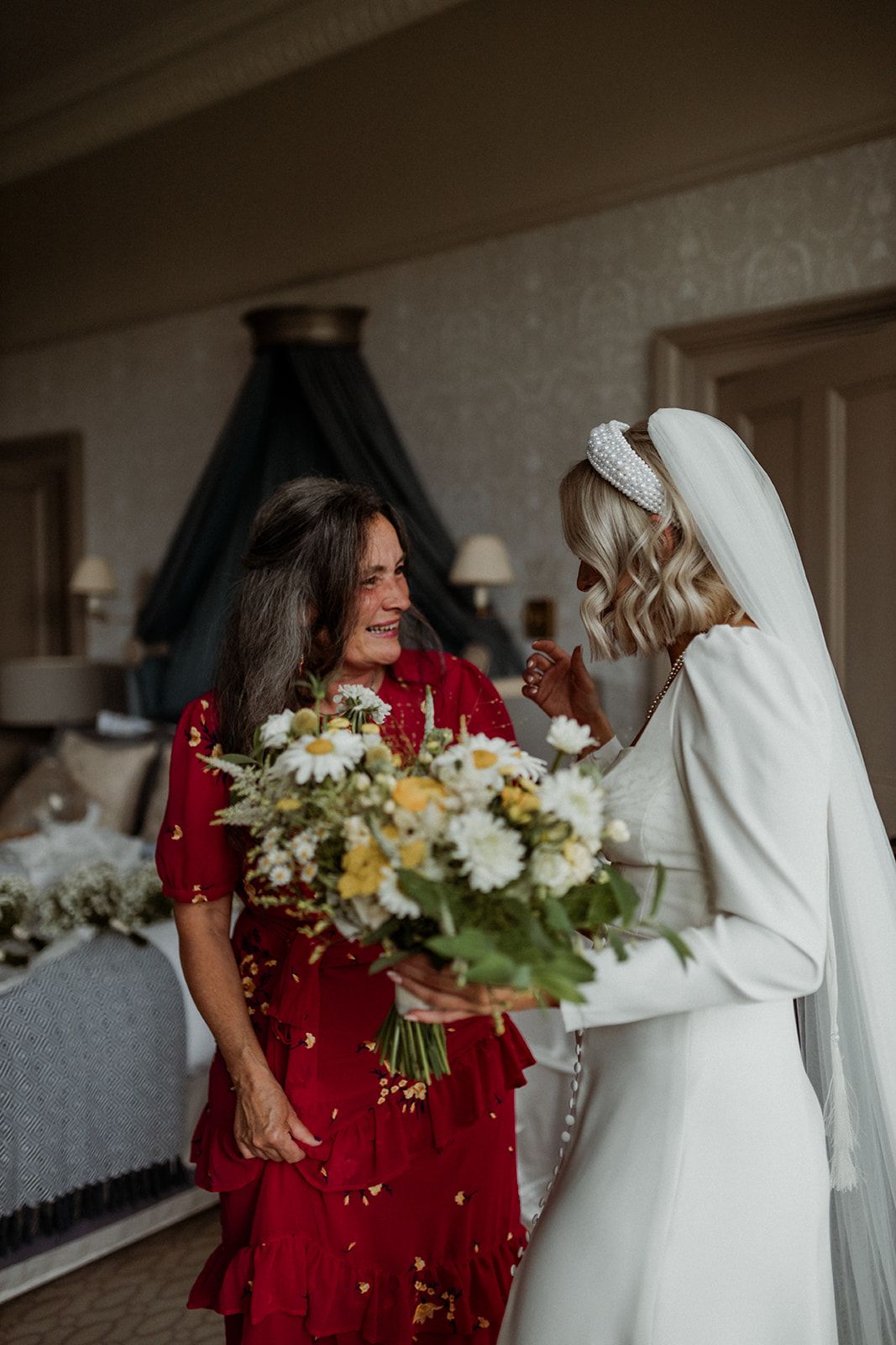 Two people share a tender moment while holding beautiful floral bouquets indoors.