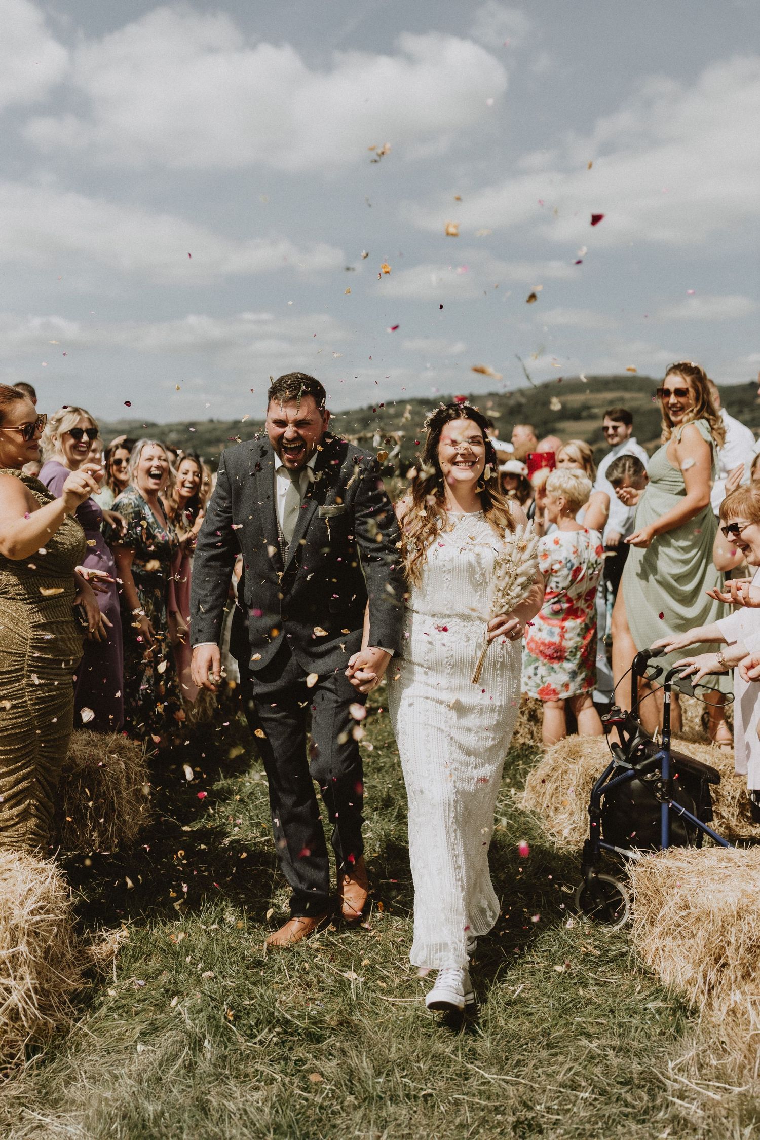 Wedding guests celebrating outdoors with colorful flower petals being tossed in the air.
