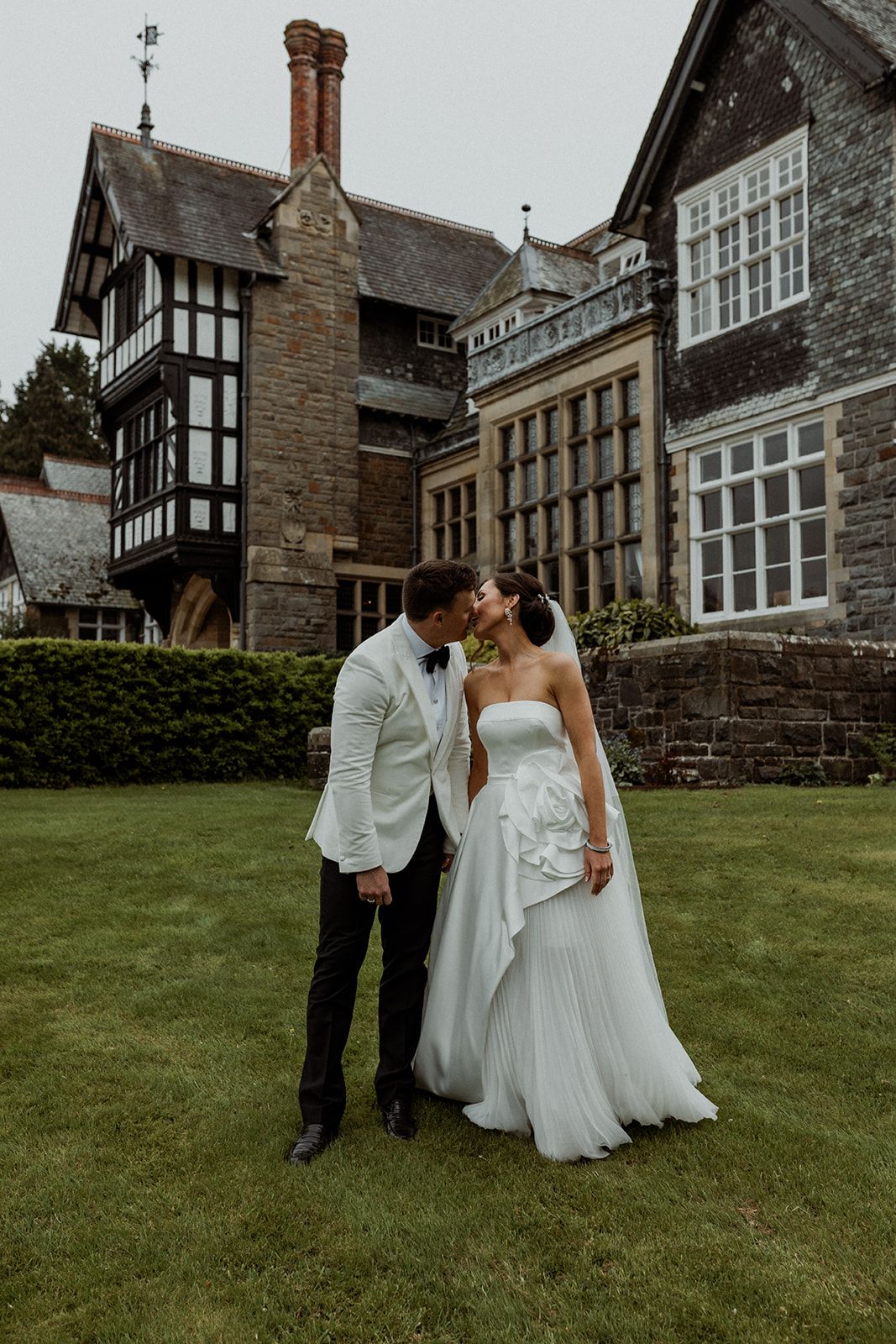 Newlyweds share romantic moments on the lawn of a beautiful stone Tudor-style mansion.