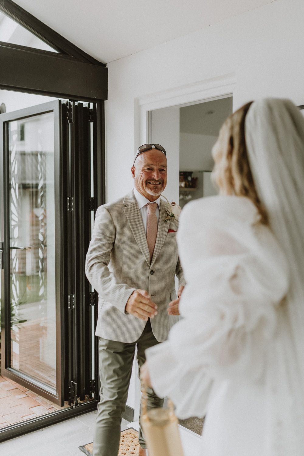 First look moment captured in bright modern room with floor-to-ceiling windows.