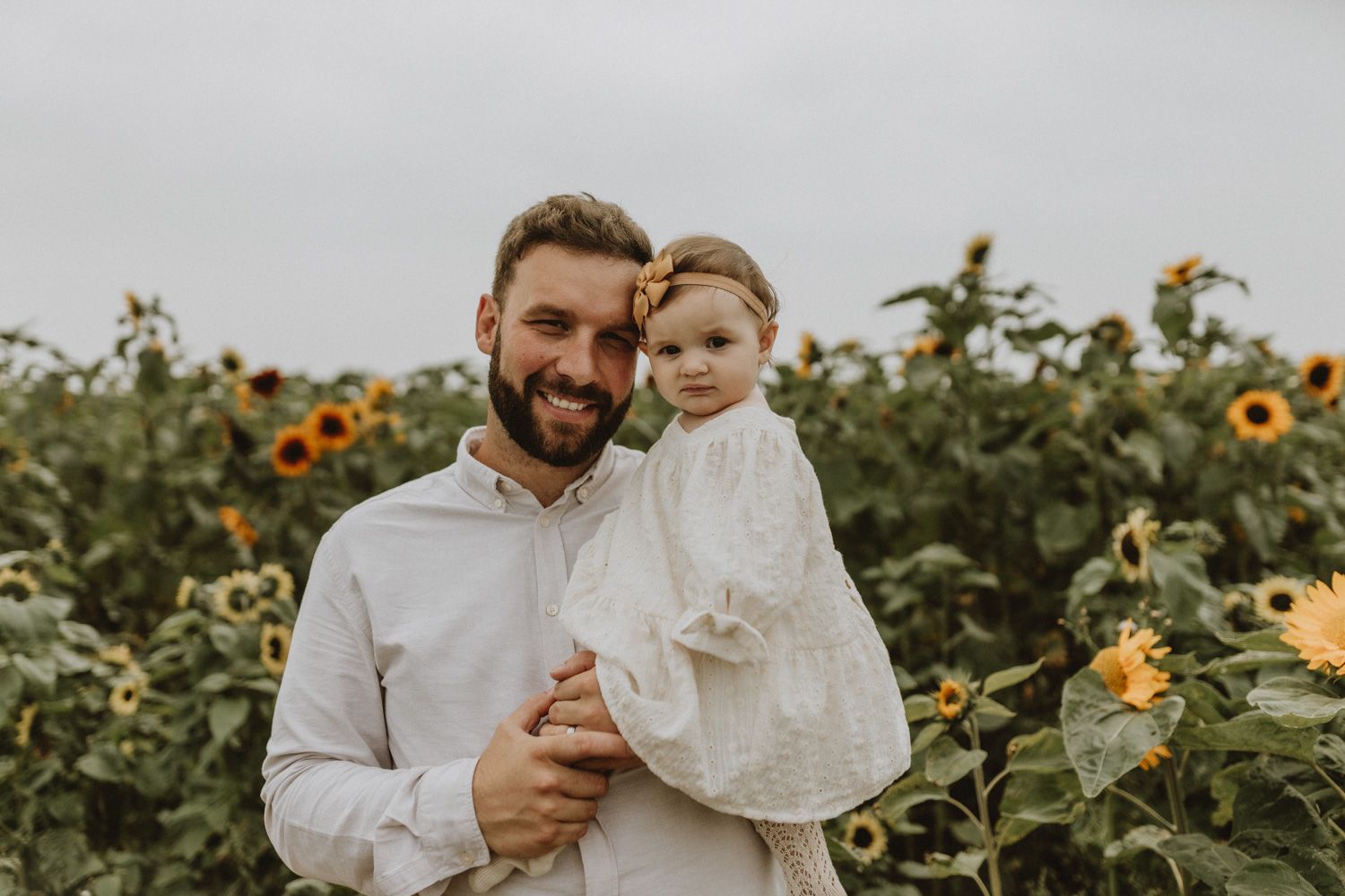 Heartwarming portrait in white clothing among blooming sunflowers.