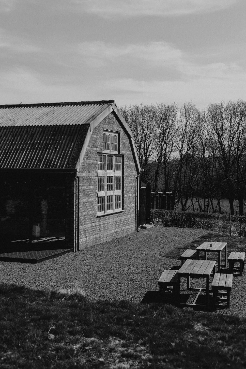 A rustic barn-style building with picnic tables outside on a cloudy day.