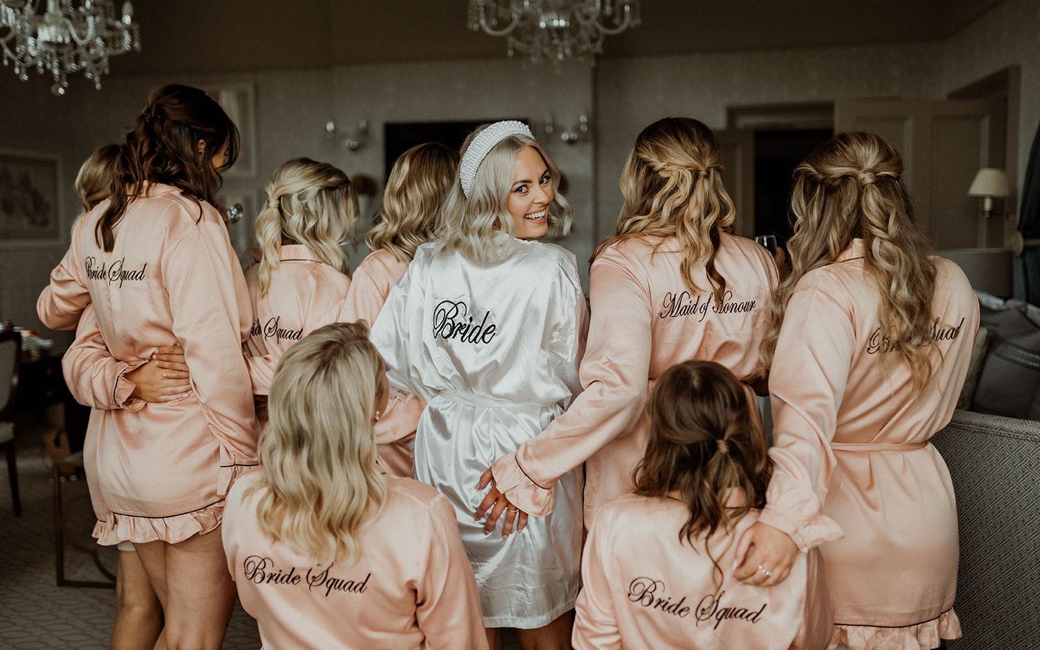 Matching pink satin robes worn by wedding party members during preparation.