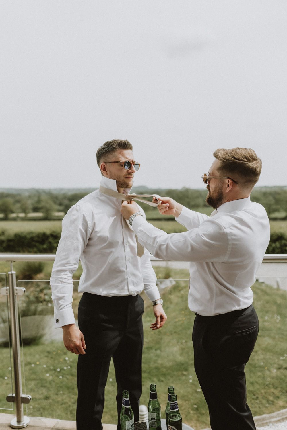 Two people in formal white shirts and black pants helping with wedding preparations outdoors.