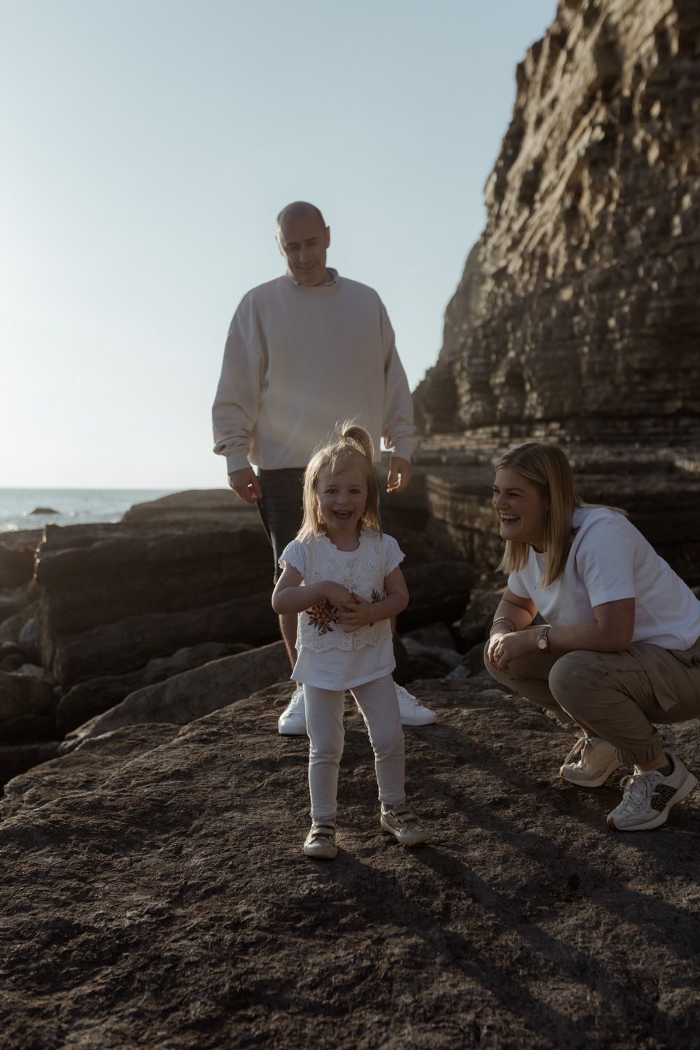 Family enjoying a moment together on rocky coastal cliffs.