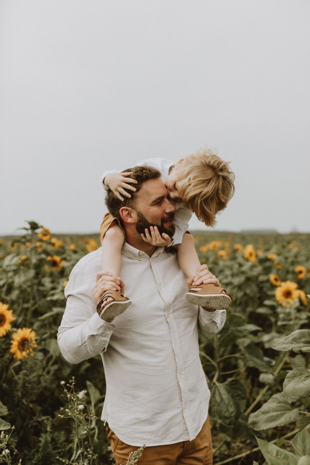 Tender embrace shared during piggyback ride among blooming sunflowers.