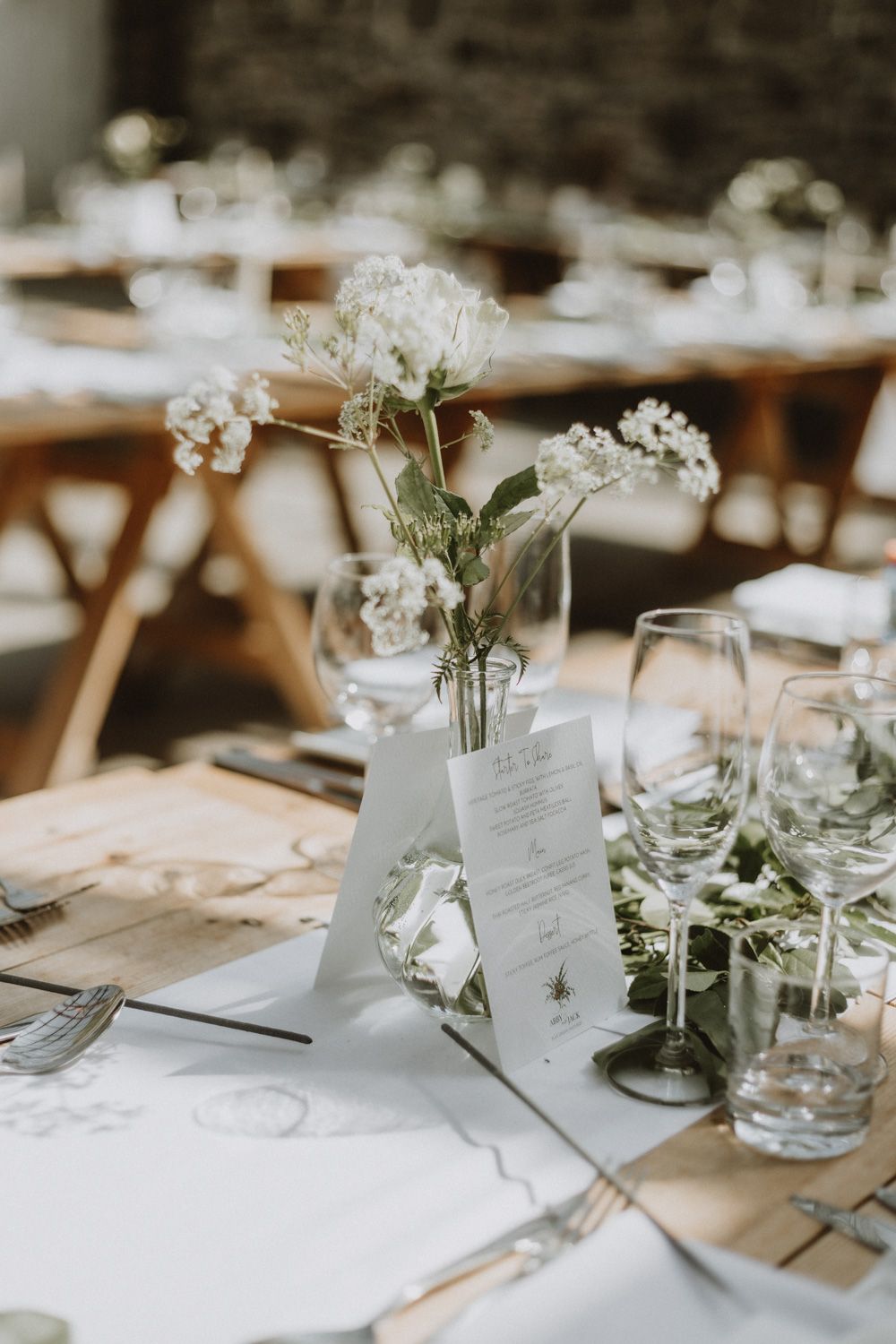 Minimalist table setting with delicate floral centerpiece and wedding menus.