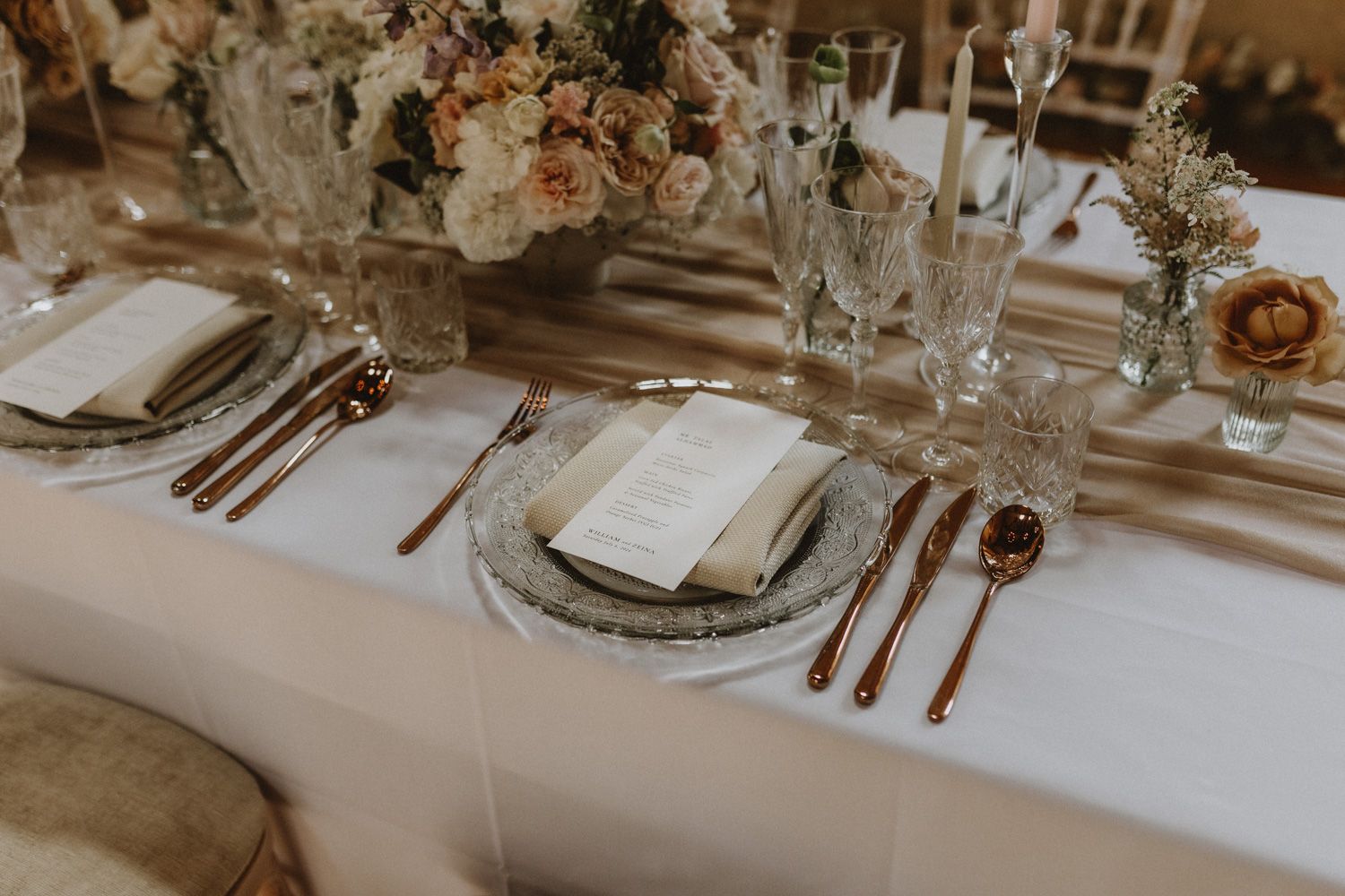 Luxurious wedding reception table decorated with roses and fine crystal glassware.
