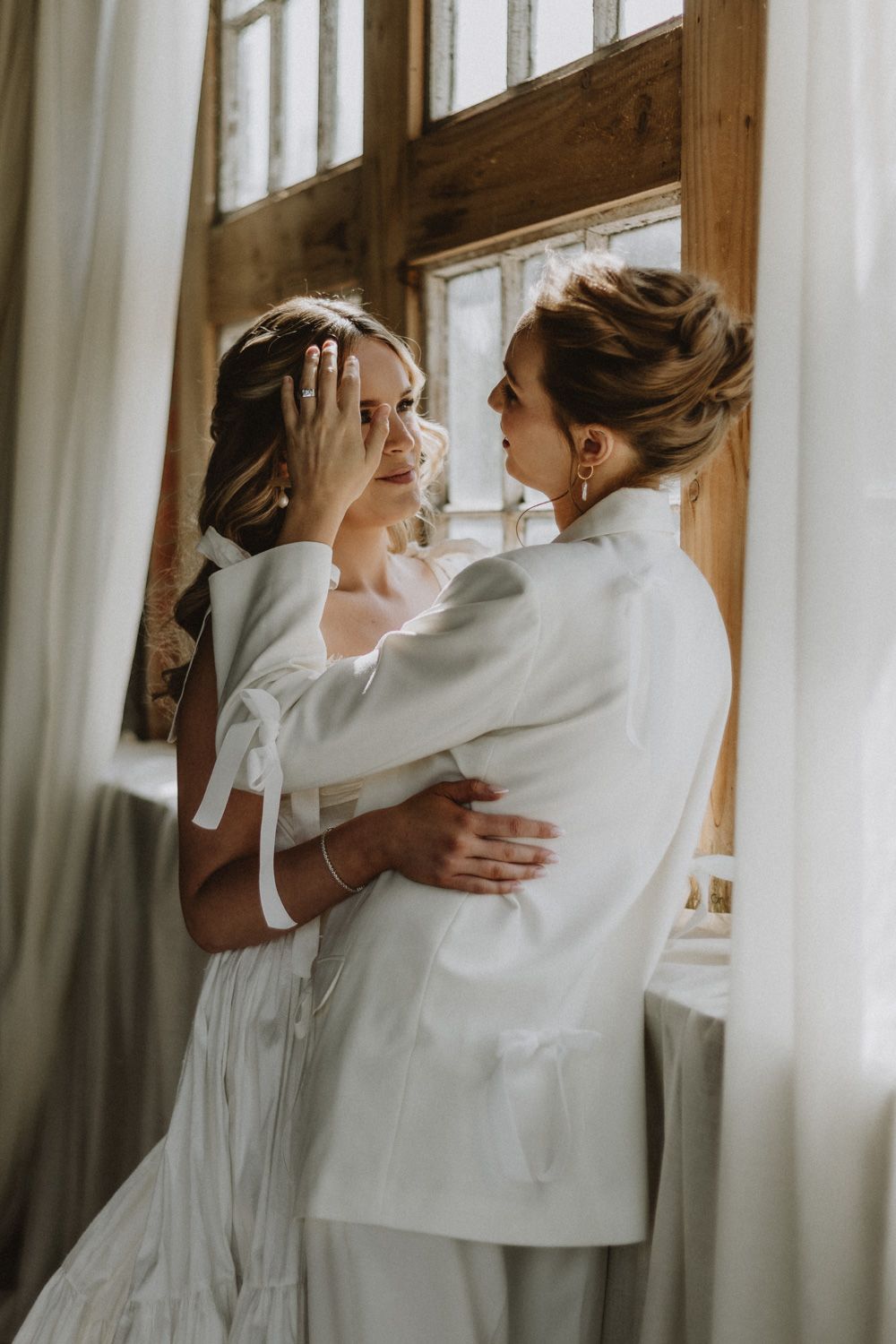 A tender embrace captured in soft natural light by a rustic window.