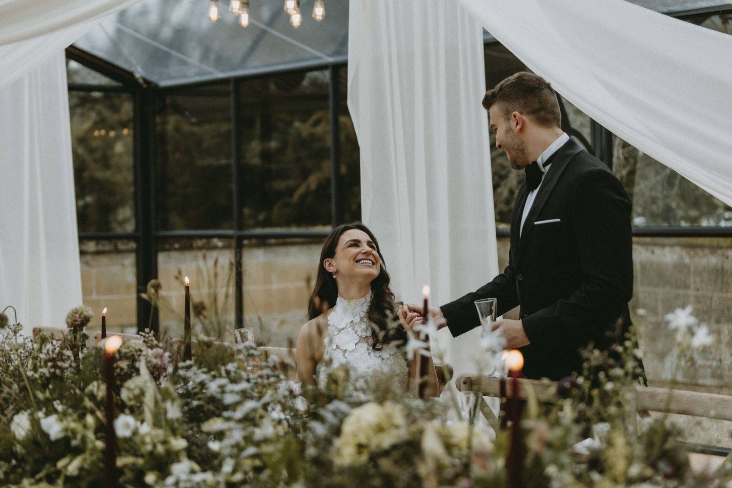A joyful wedding scene surrounded by delicate white drapes and floral arrangements.
