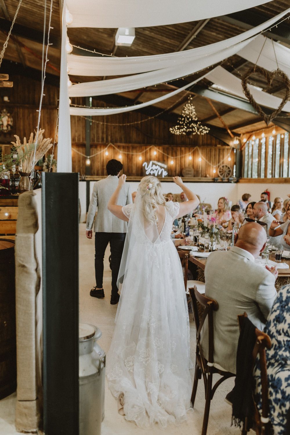 Reception venue decorated with white draping and wooden details as guests dine.