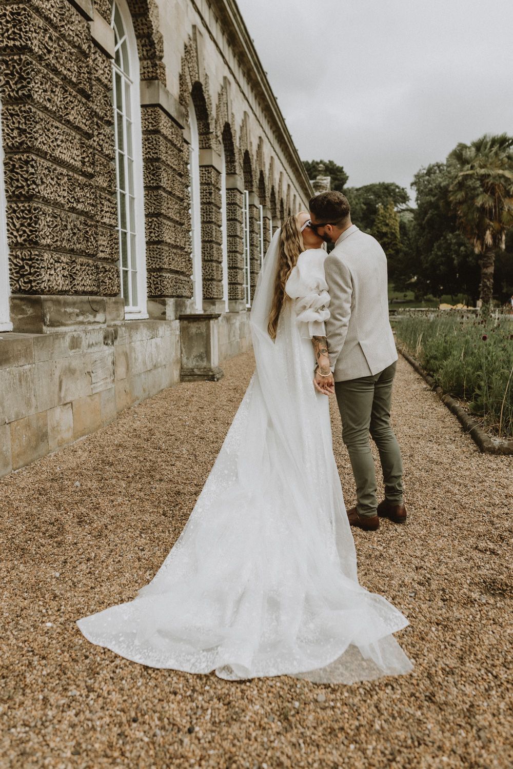 Romantic wedding portrait against historic stone building with arched windows.