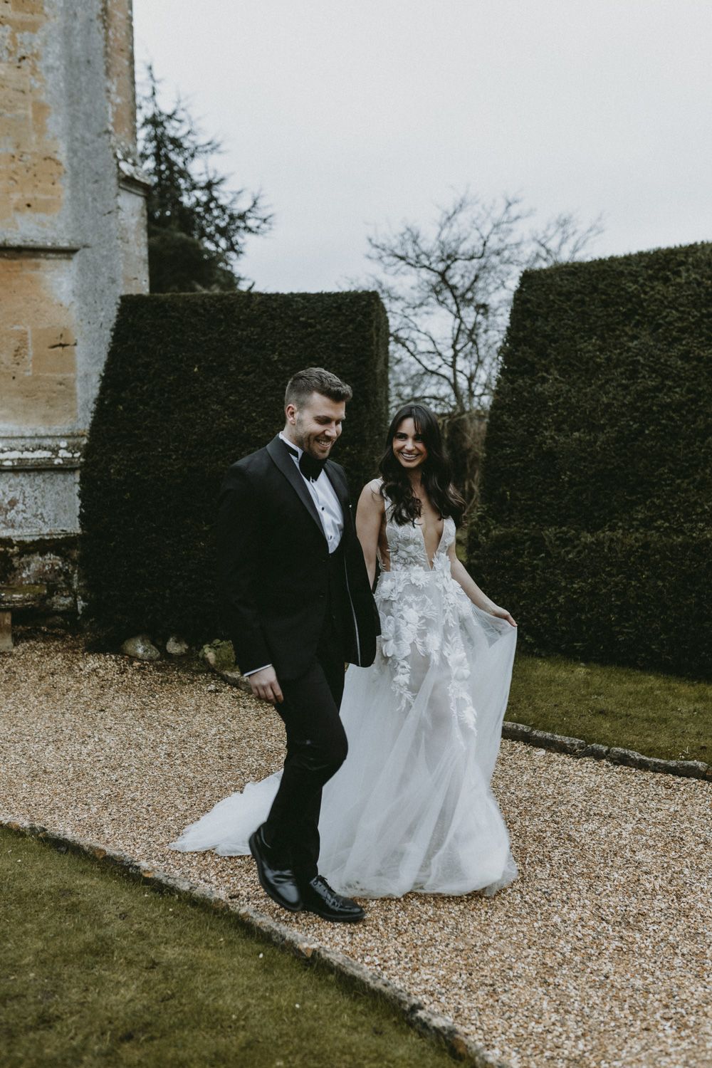 A beautiful wedding moment on a garden path with manicured hedges in the background.