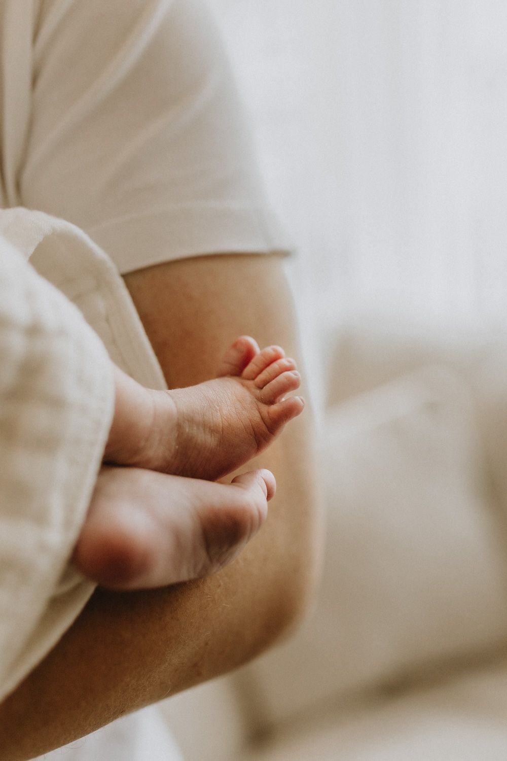 Close-up of tiny baby feet against a soft white background.