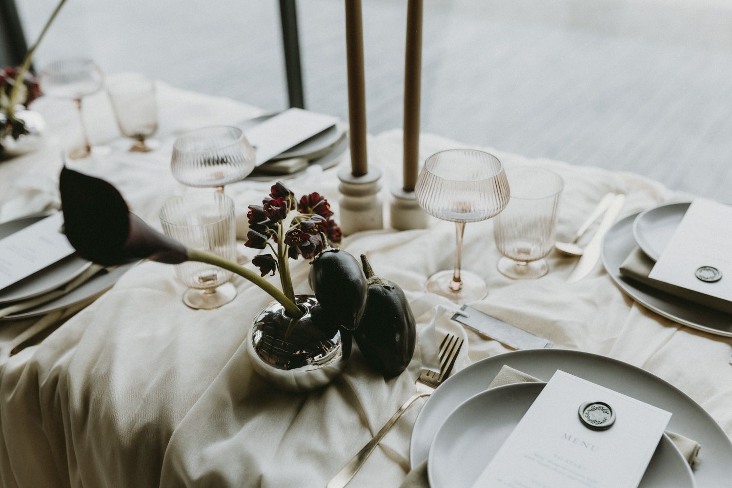 Elegant table setting with wine glasses, white linens and delicate floral centerpieces.