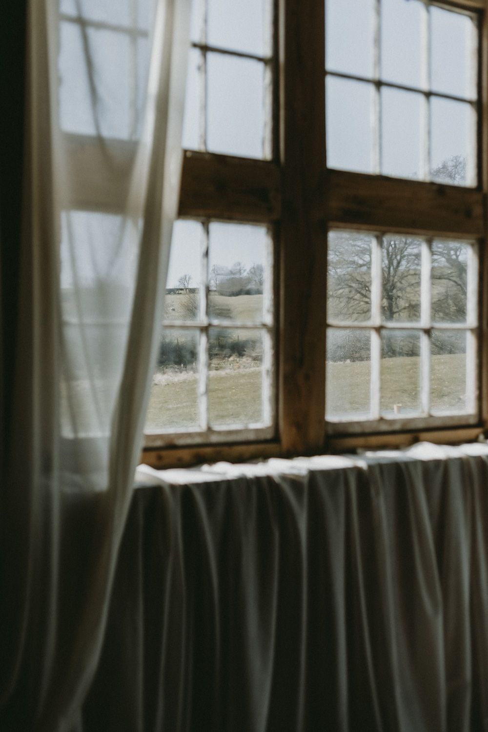 Sunlight streams through vintage windowpanes with sheer curtains creating a dreamy atmosphere.